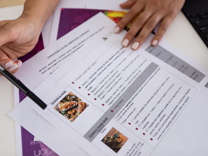 nutritionist's hands pointing at a document with nutrition details of a meal