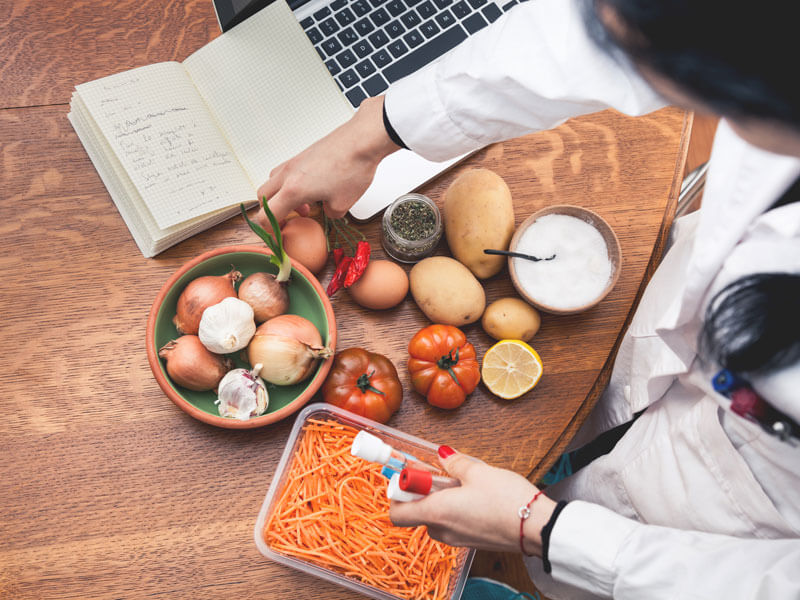 Nutritionist analyzing various produce and taking notes in a notebook