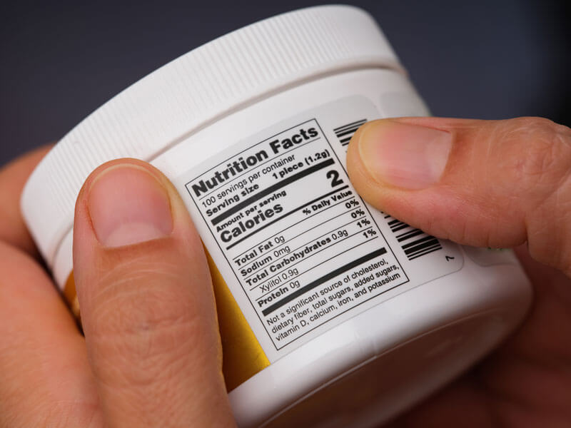 hands holding a gum container with focus on the nutrition label